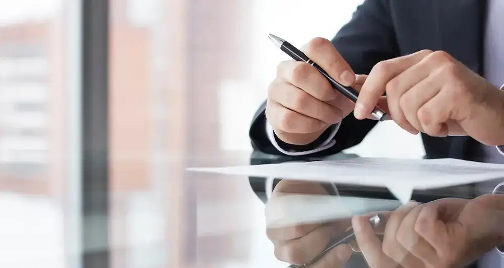 Homme en costume s'apprêtant à signer un document.